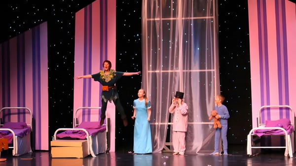 Schueler der Saint John's Prep praesentieren eine Buehnenauffuehrung mit bunten Kostuemen und einem sternenbesetzten Hintergrund.