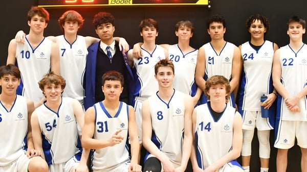 Eine Gruppe junger Basketballspieler steht in Uniform vor der Anzeigetafel auf dem Campus des Saint Kentigern College.