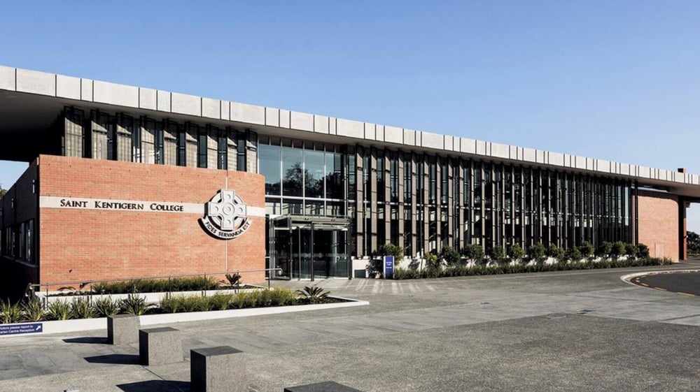 Das moderne Backstein- und Glasgebäude zeigt das Logo von Saint Kentigern College und ist von einem gepflasterten Bereich umgeben.