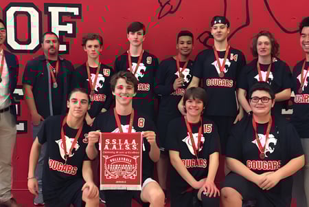 Eine Gruppe von Schülerinnen und Schülern posiert vor rotem Hintergrund mit dem Logo der Saint-Lambert International High School.