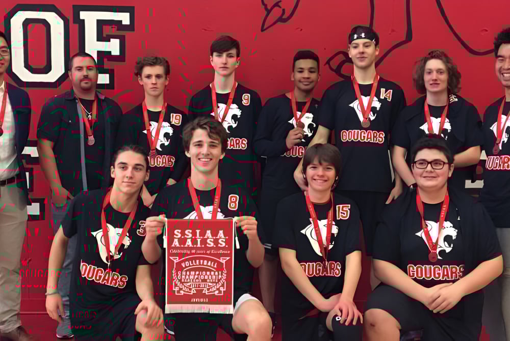 Eine Gruppe von Schülerinnen und Schülern posiert vor rotem Hintergrund mit dem Logo der Saint-Lambert International High School.