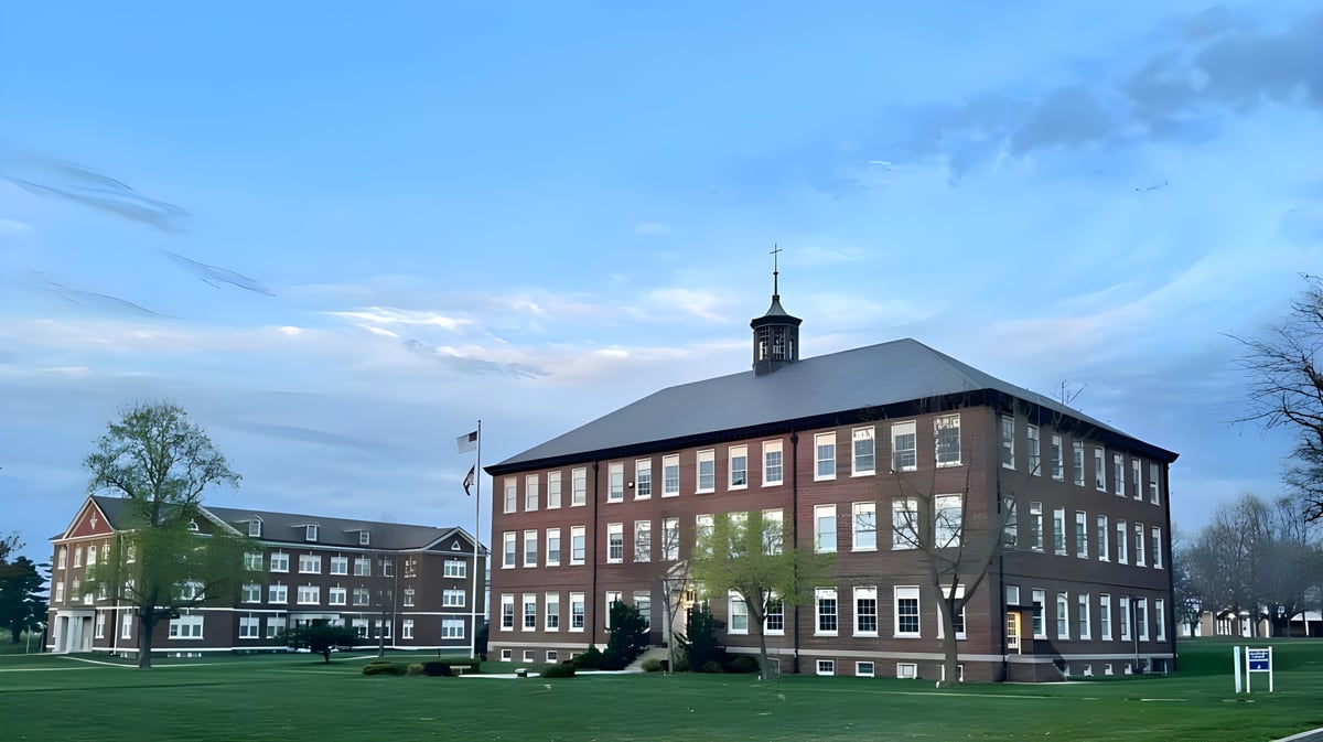Das mehrstöckige Backsteingebäude mit Uhrturm auf dem Campus der Saint Paul Lutheran High School ist von einer Wiese umgeben.