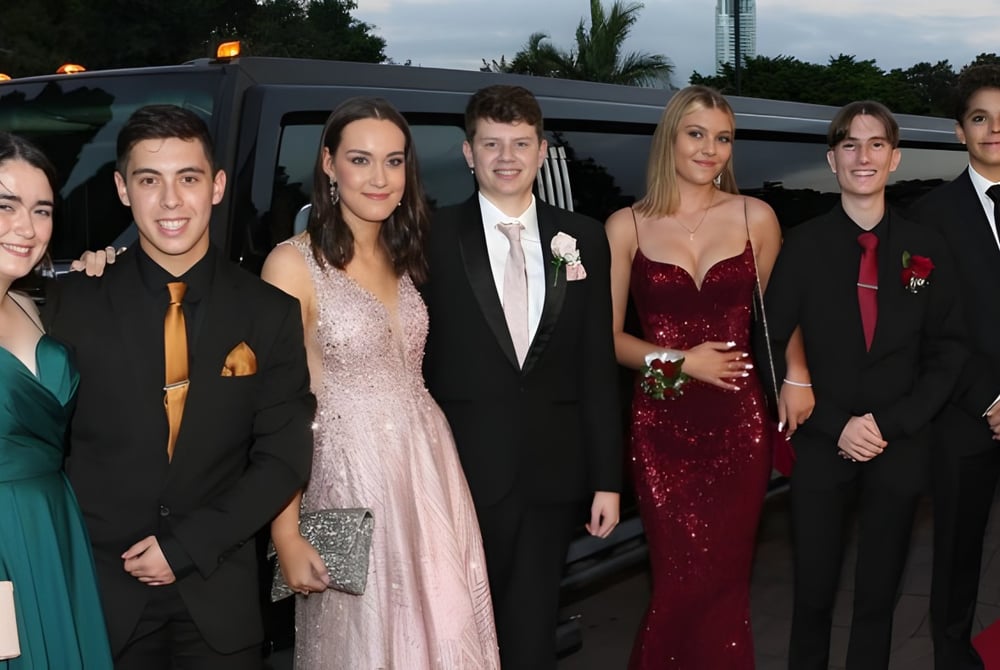 Eine Gruppe von gut gekleideten Schülerinnen und Schülern des Saint Stephen’s College posiert vor einer Limousine bei einer Schulveranstaltung.