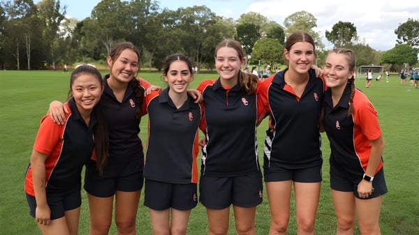 Eine Gruppe junger Schülerinnen steht im Sportoutfit auf einem Rasenfeld auf dem Campus von Saint Stephen’s College.