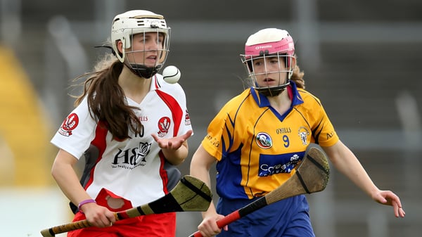 Zwei Schülerinnen der Salerno Secondary School stehen in Hockeyuniformen auf dem Hockeyfeld einer Sportarena.