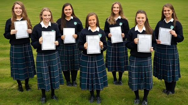 Eine Gruppe von Schülerinnen der Salerno Secondary School steht auf einem Rasenfeld und hält Zertifikate in den Händen.