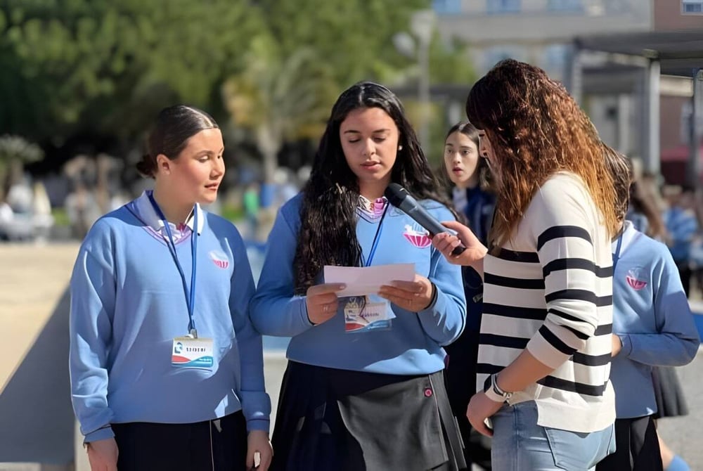 Drei Schülerinnen der Salesianas stehen gemeinsam draußen mit Stadtstraße und Gebäuden im Hintergrund.
