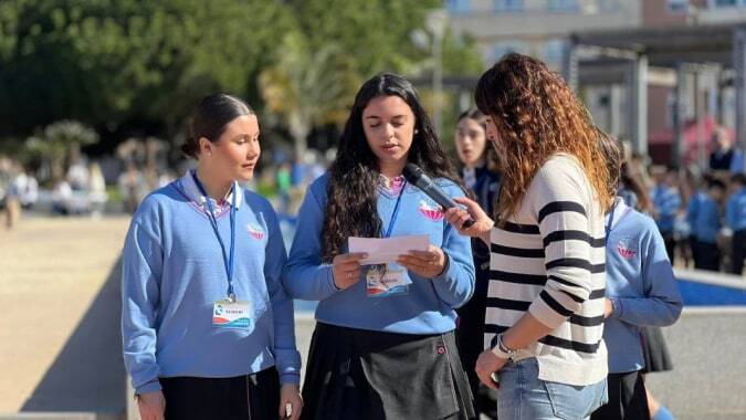 Drei Schülerinnen der Salesianas stehen im Außenbereich der Schule und unterhalten sich vor einem Schulgebäude.