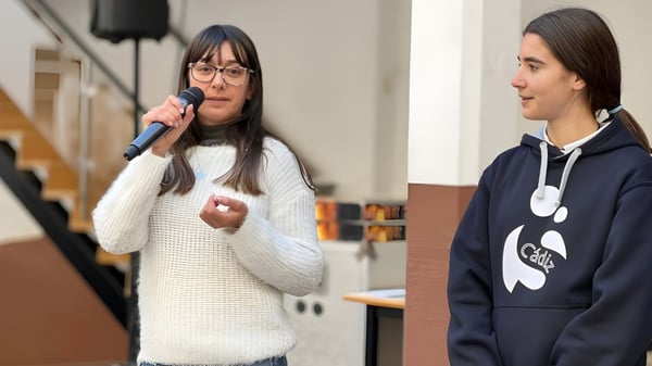 Zwei Schülerinnen der Salesianas stehen in einem Klassenraum mit Tischen und Stühlen im Hintergrund.