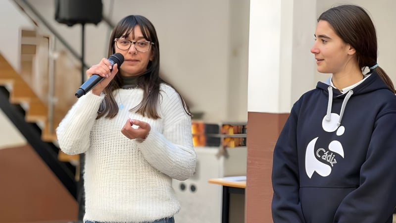 Zwei Schülerinnen der Salesianas stehen in einem Klassenraum mit Tischen und Stühlen im Hintergrund.