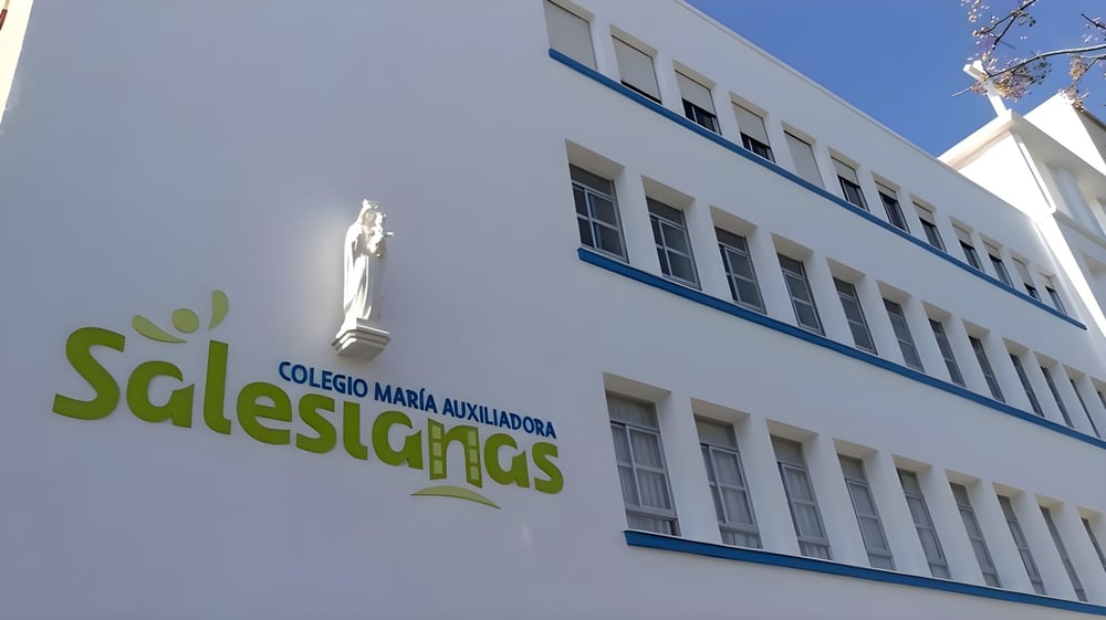 Das mehrstöckige Schulgebäude mit großem grünem Logo zeigt die Salesianas Schule.