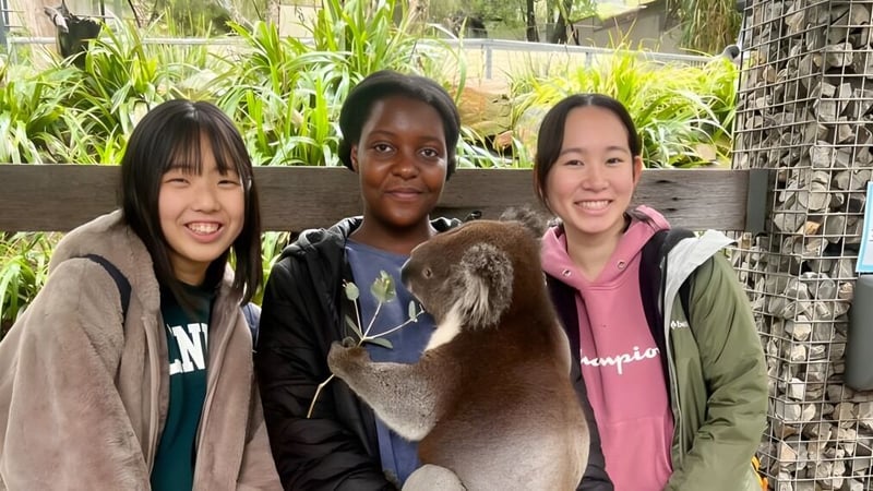 Drei Schüler der Salisbury East High School stehen vor einem grünen Garten und unterhalten sich freundlich.