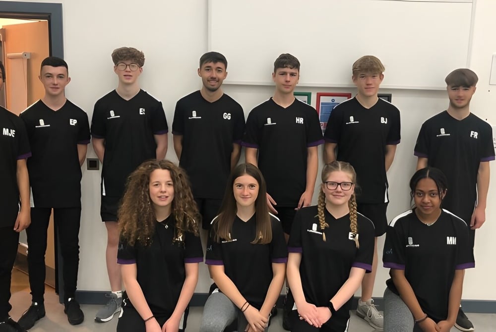 Eine Gruppe von Schülern in schwarzen Shirts steht gemeinsam in einem Klassenraum des Salisbury Sixth Form College.