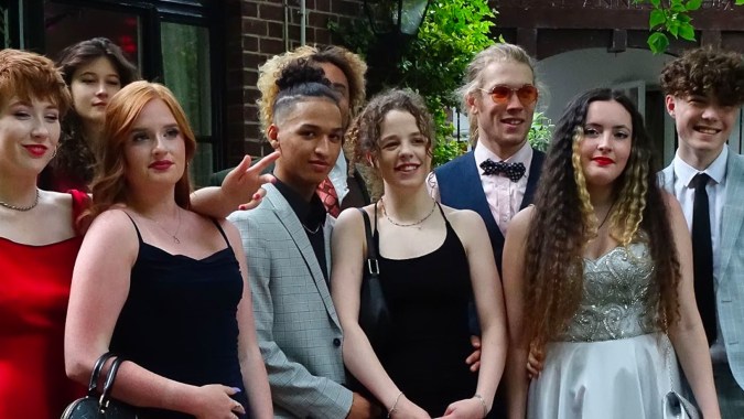 Eine Gruppe von Personen vor dem Backsteingebäude des Salisbury Sixth Form College mit Grünpflanzen im Hintergrund.