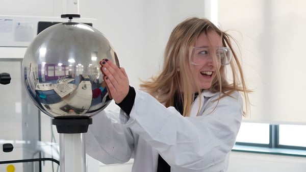 Eine Schülerin des Salisbury Sixth Form College untersucht begeistert ein reflektierendes Glasgefäß im Labor.