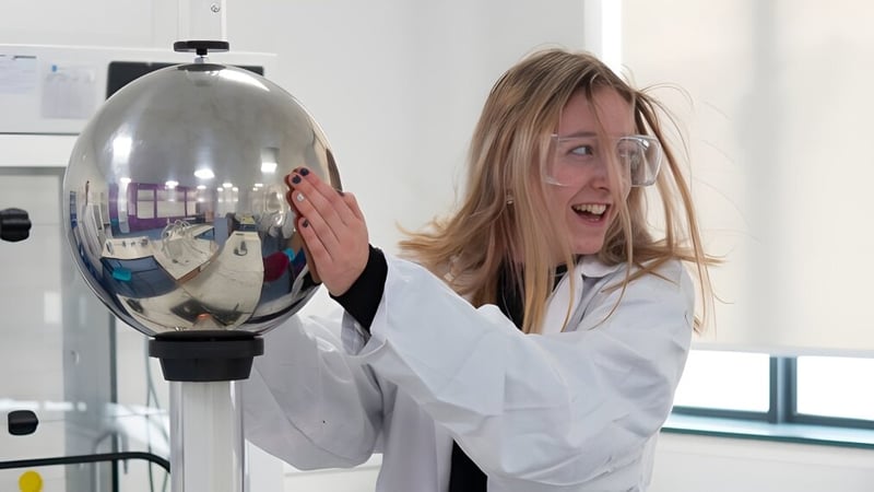 Eine Schülerin des Salisbury Sixth Form College untersucht begeistert ein reflektierendes Glasgefäß im Labor.