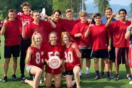 Eine Gruppe von Schülerinnen und Schülern der Samuel Robertson Secondary School steht auf einem Sportfeld mit roter Sportkleidung.