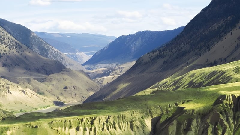 Ein grünes Tal zwischen Bergen mit Wasser im Hintergrund nahe der Samuel Robertson Secondary School.