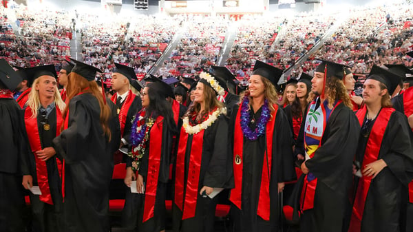 Absolventen der San Diego State University stehen in roten und schwarzen Roben gemeinsam während der Abschlussfeier.