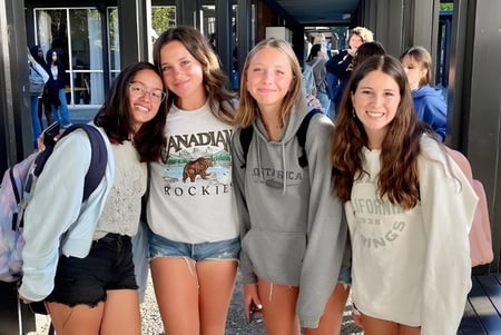 Eine Gruppe Schülerinnen posiert vor einem Gebäude mit großen Fenstern auf dem Campus der San Domenico School.