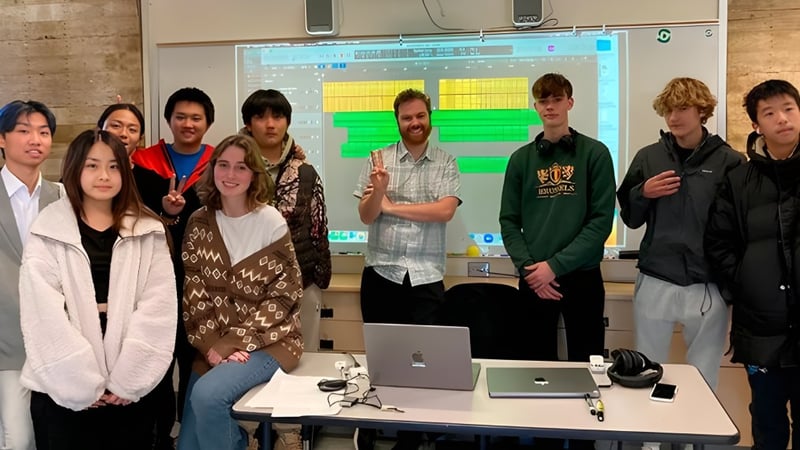 Schüler der San Domenico School arbeiten gemeinsam an Laptops in einem Klassenraum mit großem Bildschirm.