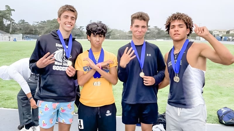 Vier Jungen in Sportkleidung mit Medaillen stehen auf einem Feld im San Luis Coastal Unified School District.