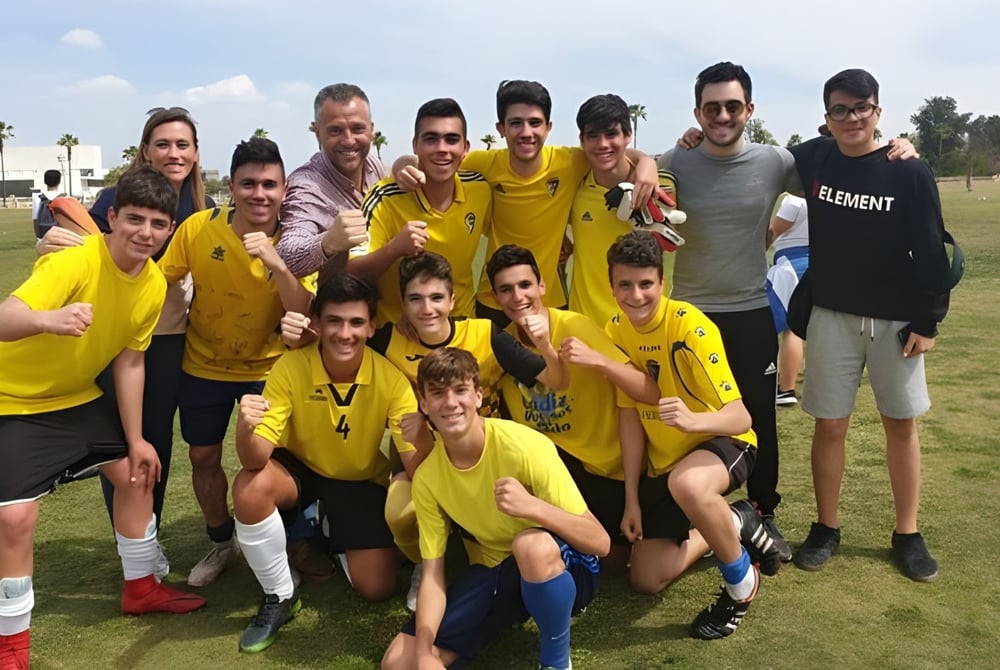 Eine Gruppe von Schülern in Gelb-Schwarzen Trikots posiert auf dem Rasenfeld auf dem Campus der San Vicente de Paul Schule.