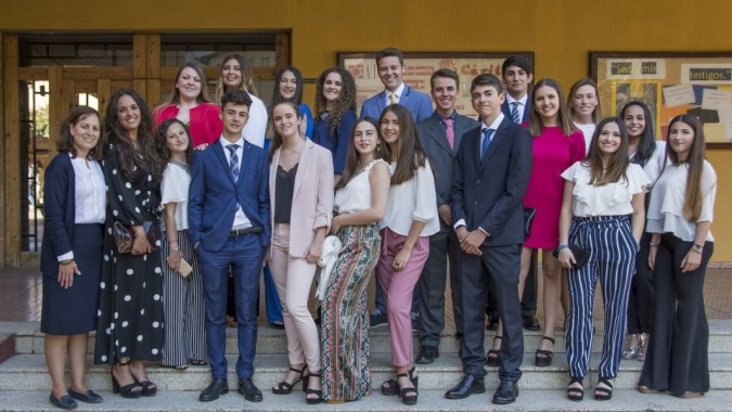 Eine Gruppe von Schülerinnen und Schülern steht gemeinsam im formellen Umfeld der San Vicente de Paul Schule mit hölzernem Hintergrund.