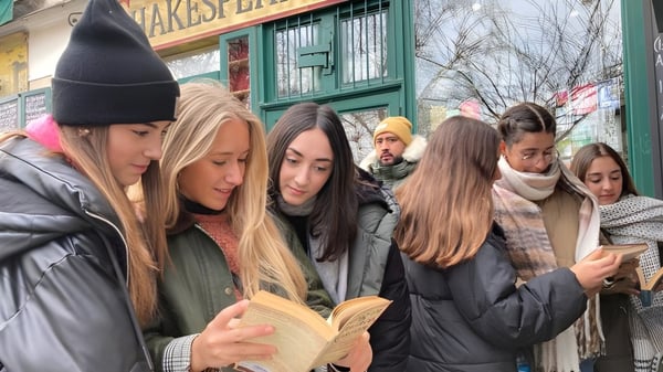 Eine Gruppe von Schülerinnen und Schülern der San Vicente de Paul School steht draußen vor einem Laden, einige lesen Bücher, andere nutzen mobile Geräte.