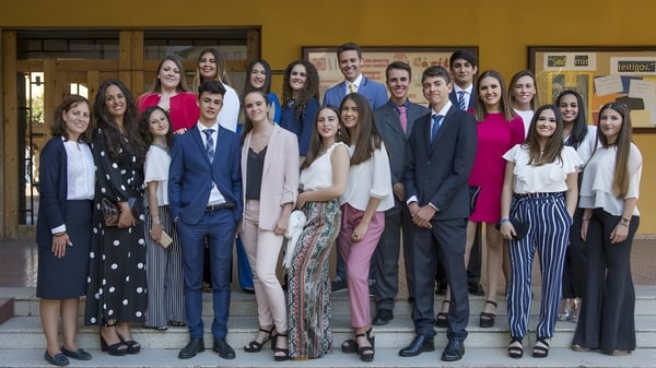 Eine Gruppe von Schülerinnen und Schülern steht in einem Holzraum mit gerahmten Bildern an der Wand auf dem Campus der San Vicente de Paul Schule.