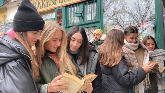 Schüler der San Vicente de Paul stehen im Winter draußen vor einem Laden und lesen Bücher.