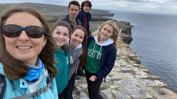 Eine Gruppe von Schülerinnen und Schülern des Sancta Maria College macht ein Selfie vor einer Küstenlandschaft mit Klippen und Meer im Hintergrund.