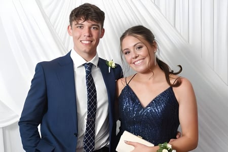 Ein junges Paar posiert in formeller Kleidung vor einem weißen Vorhang auf dem Campus von Sancta Maria College.