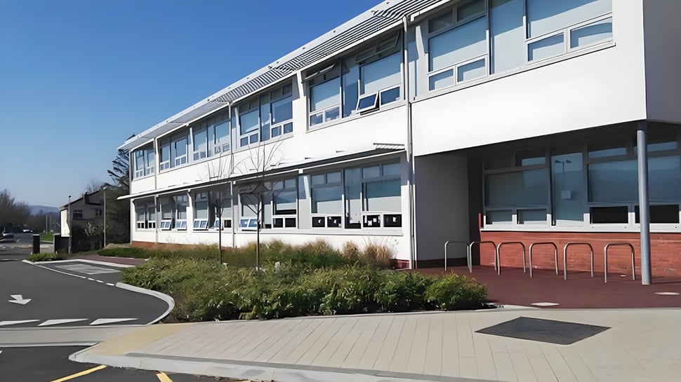 Das moderne mehrstöckige Gebäude des Sancta Maria College Ballyroan mit großen Fenstern und einer gepflasterten Wegführung im Vordergrund.