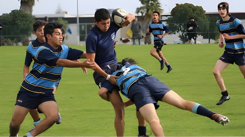 Schüler des Sancta Maria College spielen ein Rugbyspiel auf dem Sportfeld vor den Schulgebäuden.