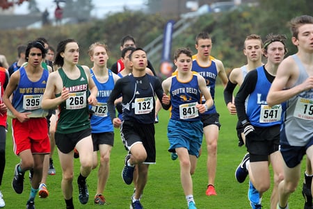 Eine Gruppe Schülerinnen und Schüler der Sands Secondary School nimmt an einem Cross-Country-Lauf auf einem Feld teil.