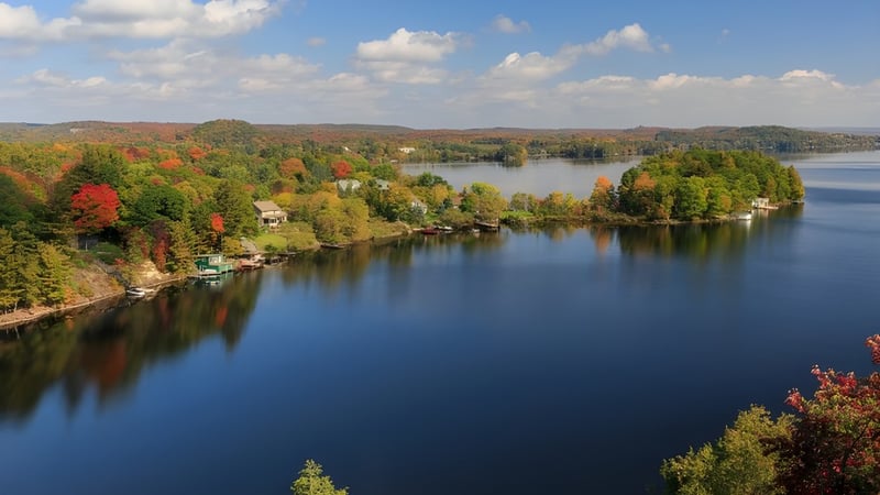 Ein ruhiger See mit buntem Herbstlaub und sanften Hügeln im Hintergrund auf dem Gelände der Sandwich Secondary School.