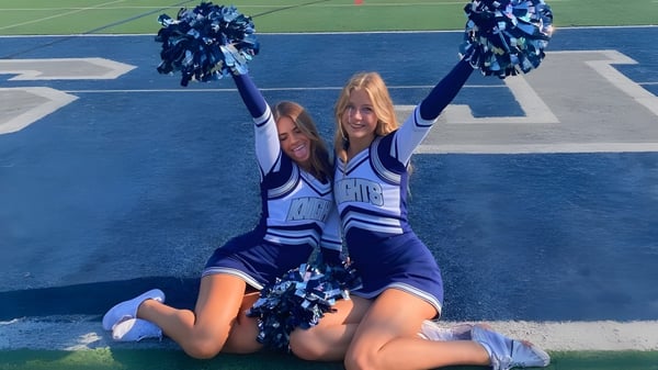 Zwei Cheerleader führen auf dem Sportfeld des Santa Barbara Unified School District eine Choreografie in blauen und weißen Uniformen auf.