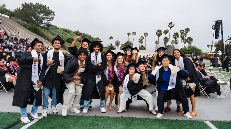 Eine Gruppe von Absolventinnen und Absolventen des Santa Barbara City College posiert im Freien vor Bäumen und einer Wiese.