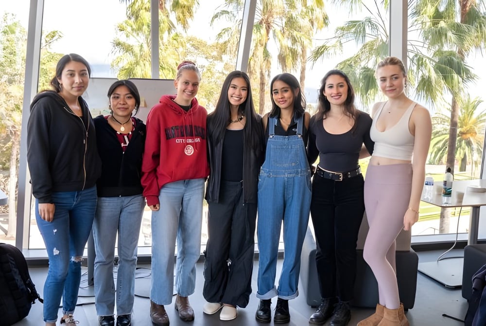 Eine Gruppe von sechs Schülerinnen steht vor Palmen auf dem Campus des Santa Barbara City College.