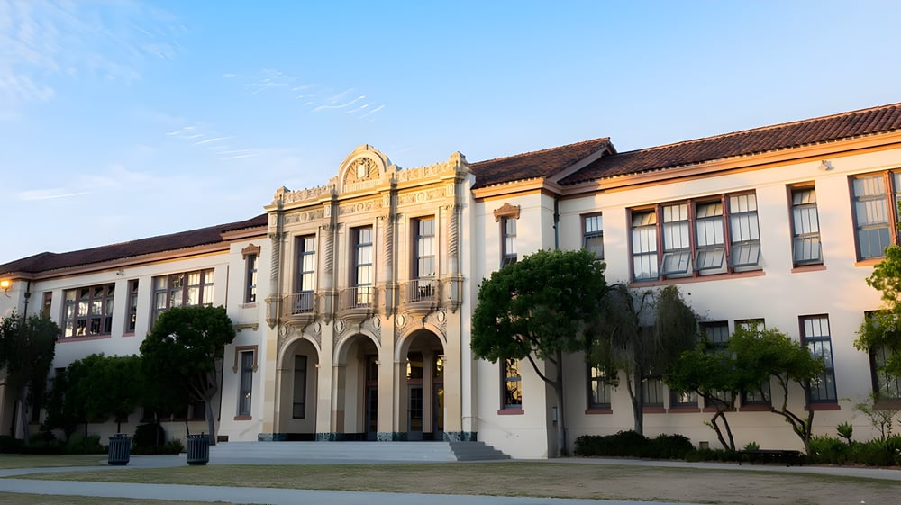 Das Hauptgebäude der Santa Barbara High School mit verzierten Fenstern steht eingebettet in eine bewachsene Grünanlage.
