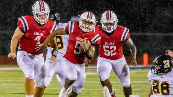 Schüler der Santiam Christian School laufen nachts auf dem Fußballfeld während eines Spiels.