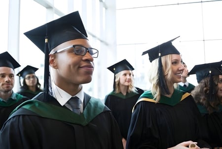Eine Gruppe von Absolventinnen und Absolventen der Santiam Christian School steht in der Halle vor großen Fenstern in akademischer Kleidung.