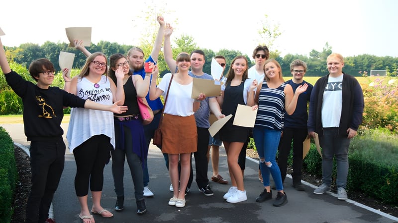 Eine Gruppe von Schülerinnen und Schülern steht gemeinsam in einer natürlichen Umgebung auf dem Gelände der Sarum Academy.