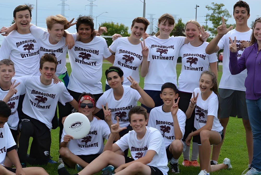 Eine Gruppe von Schülerinnen und Schülern der Saunders Secondary School versammelt sich auf einer Wiese, einige sitzen, andere stehen.