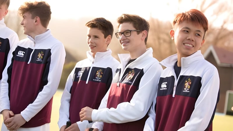 Eine Gruppe Schüler des Scarborough College steht im Freien in Schuluniformen mit weißen Hemden und burgunderroten Pullovern.
