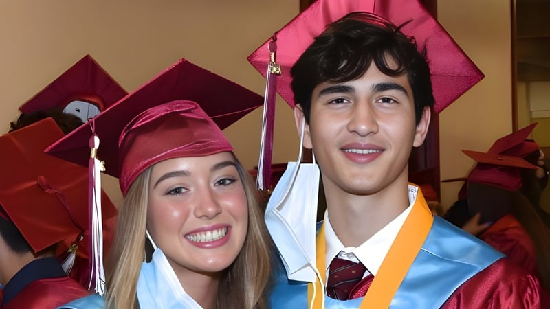 Zwei Absolventen der Scecina Memorial High School in Talaren posieren gemeinsam bei der Abschlussfeier.