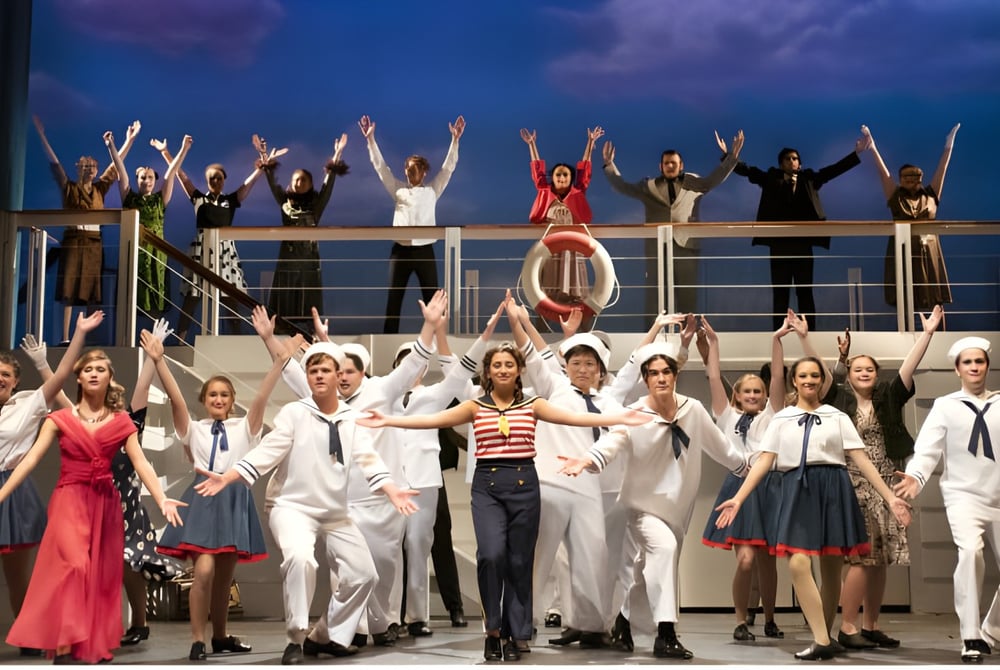 Eine Gruppe von Schülerinnen und Schülern des Schull Community College steht in verschiedenen Kostümen auf einer Bühne vor einem wolkigen Himmel.