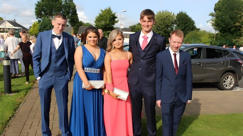 Eine Gruppe von Personen steht auf einem Weg im Grünen auf dem Campus der Scoil Aireagail.