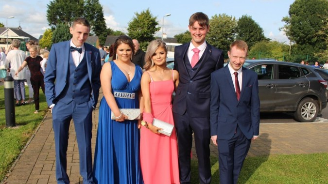 Eine Gruppe von Personen steht auf einem gepflasterten Weg umgeben von Bäumen auf dem Gelände der Scoil Aireagail.